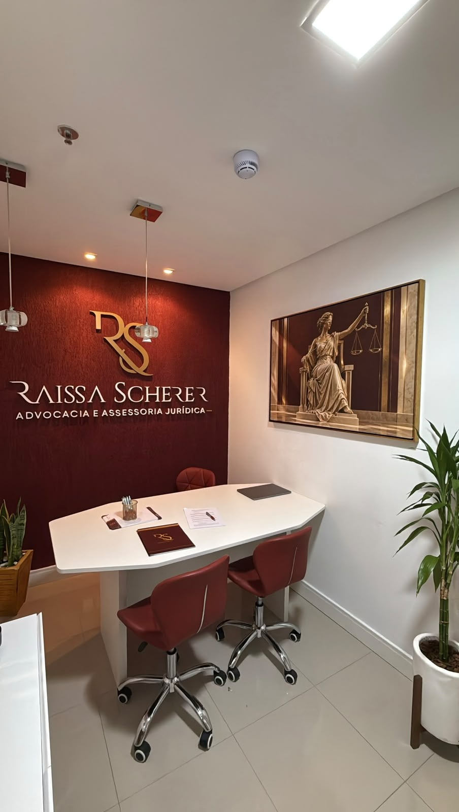 Sala de reuniões do escritório com a marca Raissa Scherer aplicada na parede bordô